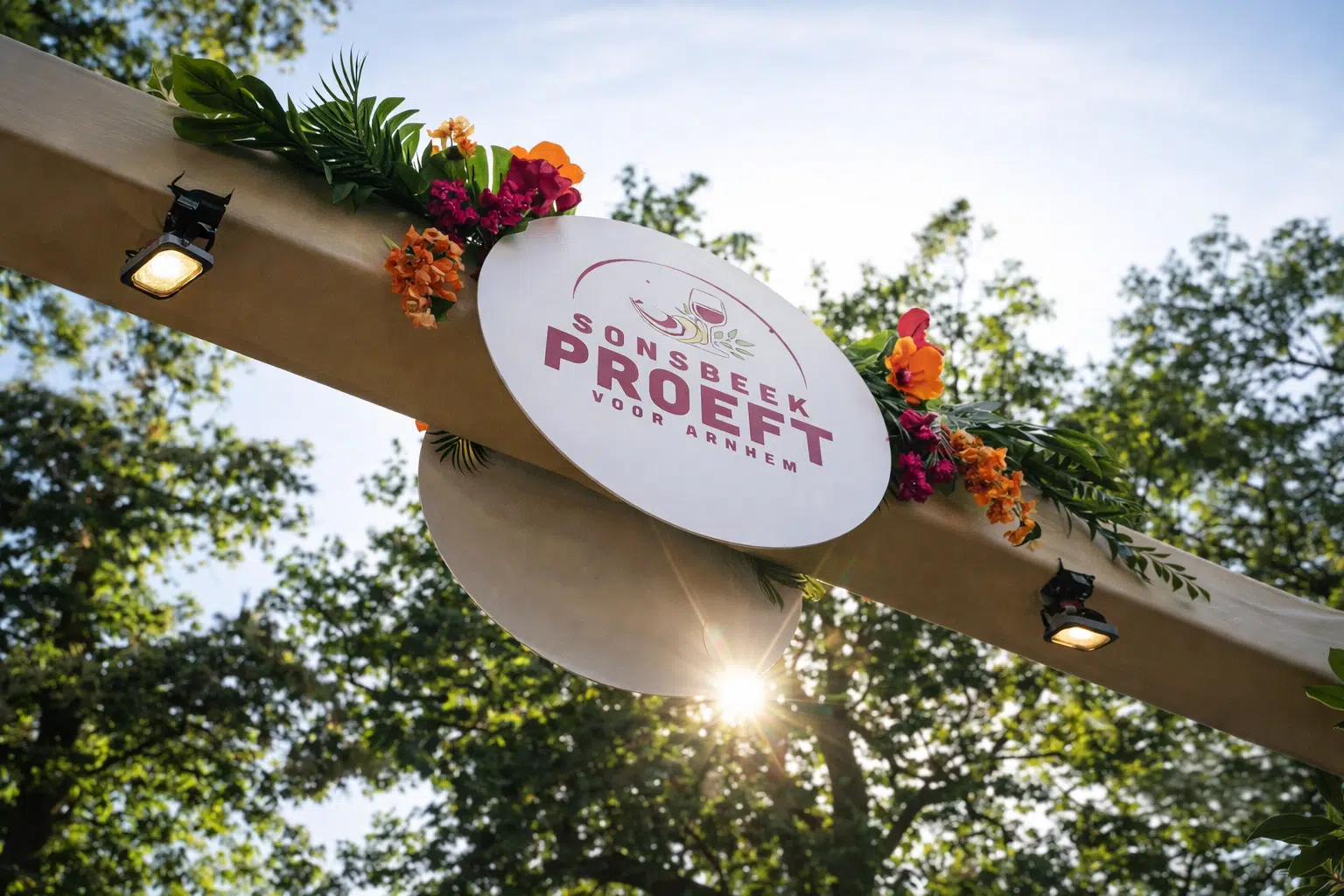 Entreeboog van SonsbeekProeft met bloemen en een rond festivalbord in Park Sonsbeek.